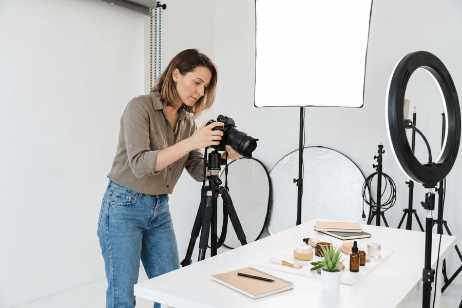 Content Creatorin richtet eine Kamera auf ein Produkt-Flat-Lay in einem professionellen Fotostudio mit Softbox.